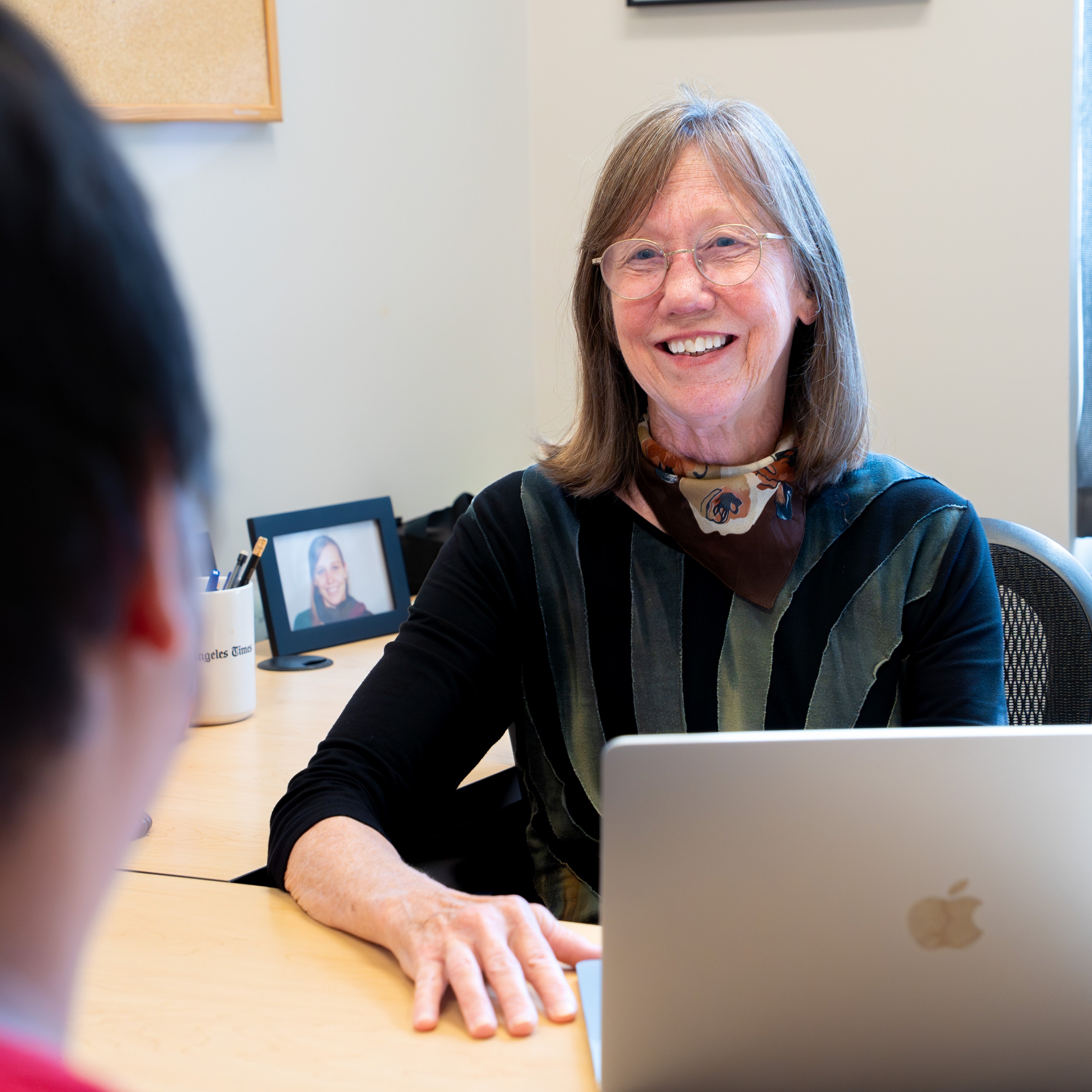 Professor Deborah Nelson, sitting in front of her computer at her desk, meets with a student in her office.