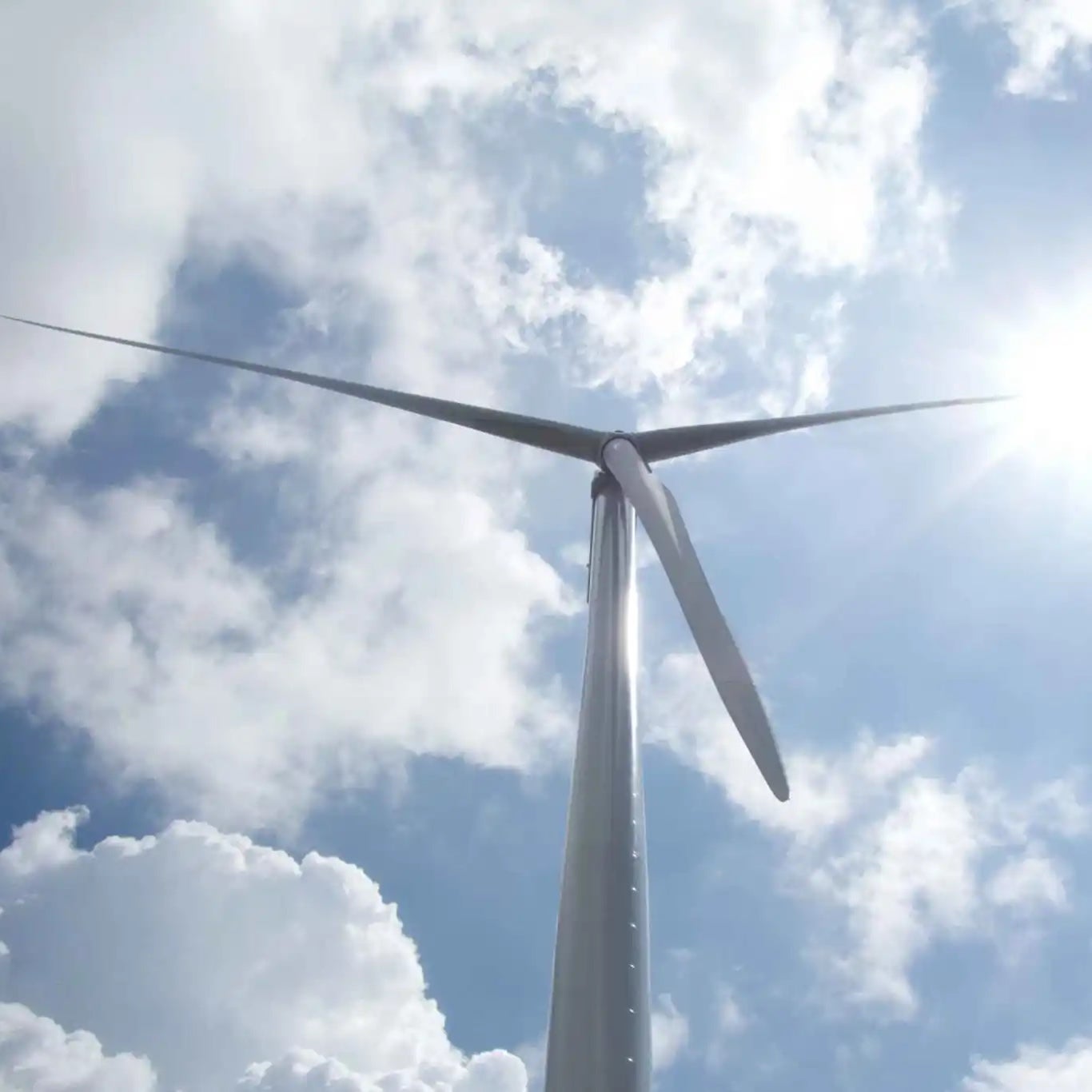 A windmill beneath a sunny, partly cloudy sky.