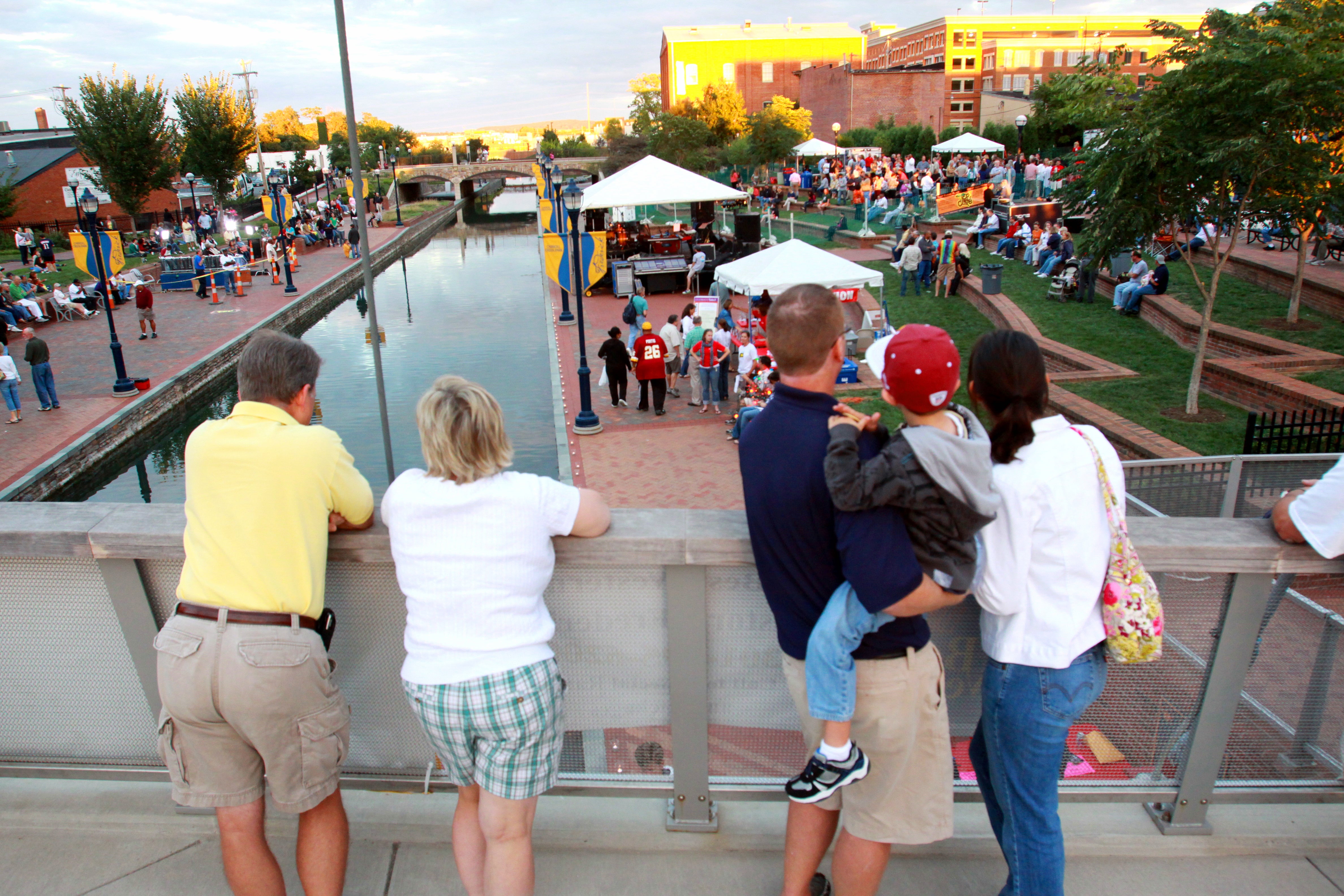 A crowd of people at an event involving tents alongside Carroll Creek in Frederick, Maryland.