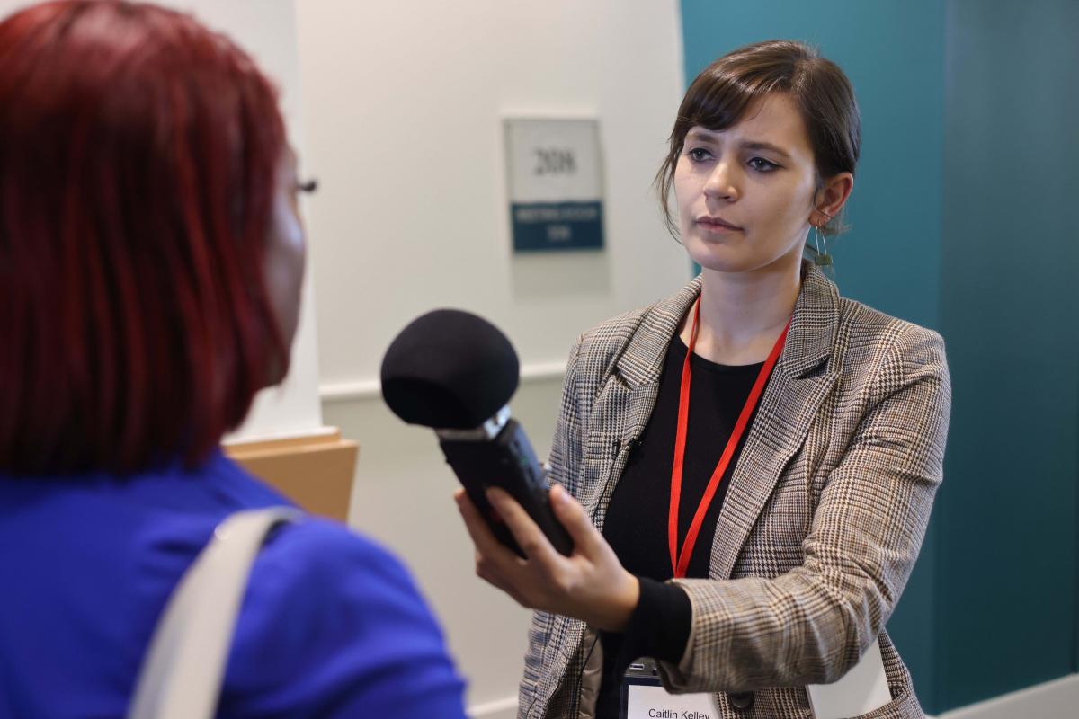 Woman student holding up a recording device while conducting an interview in an office setting