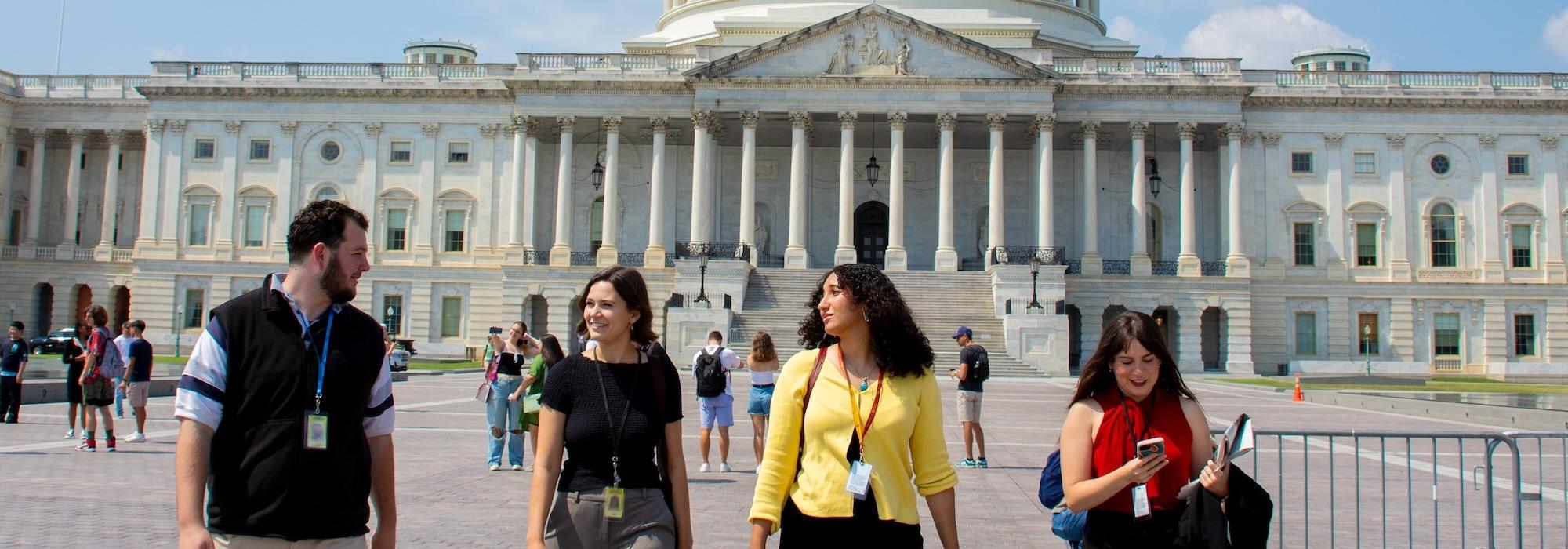 Four Capital News Service reporters smiling and talking as they walk away from the Capitol in D.C.