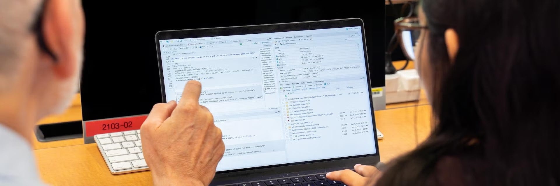 A faculty member showing a student data on a computer screen.